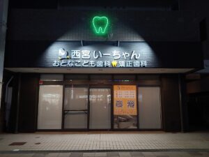 夜間発光する外照式サインと歯型ネオン管が印象的な歯科クリニックの外観施工事例｜兵庫県西宮市
