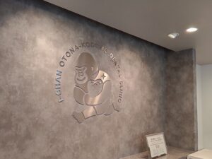 兵庫県西宮市の歯科・小児歯科・矯正歯科クリニック受付に施工したステンレスヘアライン切り文字による立体ロゴサイン施工事例