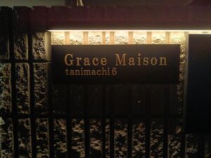 黒焼付塗装を施した真鍮館銘板をLEDライン照明で演出した高級マンションエントランスサイン
