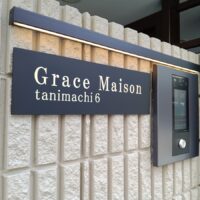 凹凸のある壁面と調和する真鍮文字の建築銘板デザイン施工事例